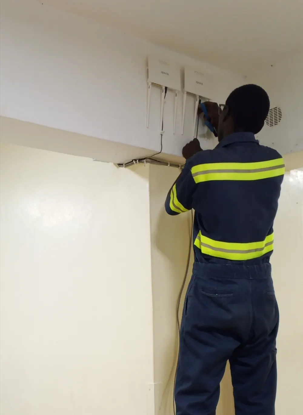 CLAUDNET technician installing wireless access points on an office wall